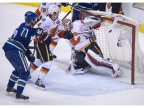 Vancouver Canucks left wing Daniel Sedin (22) tries to get a shot past Calgary Flames goalie Joni Ortio (37) as Calgary Flames defenseman Kris Russell (4) looks on during second period NHL action in Vancouver on Saturday, Jan.10, 2015.