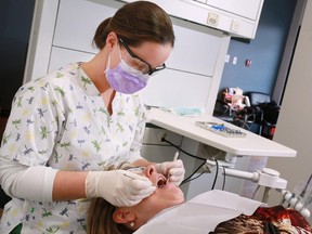 Dental hygienist Allison Keating cleans a patient's teeth in her business, Floss Dental Hygiene Care in southwest Calgary, on Monday January 26, 2015.