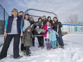 Residents of Silver Springs community, from left, Cydney Elofson, Suzanne Van Wyk, Barb Mullie, Ella Mageau, 4, Chrissy Fraser, Spencer Van Wyk, 12 days old, Stacy Van Wyk, Cathy Mageau, Carmen Horvat, 8, Martine Evanson, 4, Nia Lefebrve, and Blanka Evanson, sit on the diving board at the dive pool they are hoping to save from demolition by the City of Calgary.