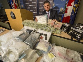 Staff Sgt. Jason Seper, with ALERT's combined forces special enforcement unit Calgary, poses with the $5 million of drugs seized in a Feb. 4, 2015 bust, which resulted in 12 arrests.