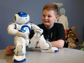 Aidan Sousa, 9, with a MEDi robot at the Alberta Children's Hospital in Calgary.