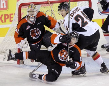 Calgary Hitmen Carson Twarynski, right, collides with Medicine Hat Tigers goalie Nick Schneider, left and Tigers David Quenneville during their game at the Scotiabank Saddldome on February 17, 2015.