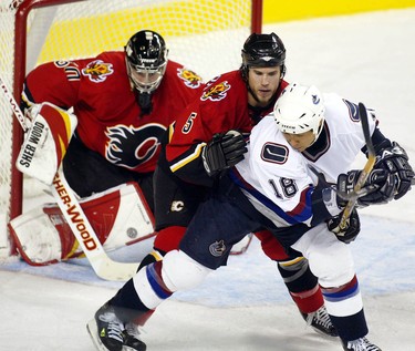 Calgary Flames Steve Montador plays keep away with Vancouver Canucks Richard Park as the puck nears goalie Philippe Sauve during the second period of play Monday night at the Pengrowth Saddledome. Photo by Jenelle Schneider