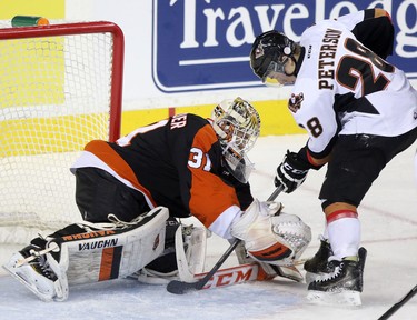 Calgary Hitmen Elliott Peterson, right, tries to get the puck in Medicine Hat Tigers goalie Nick Schneider's net during their game at the Scotiabank Saddldome on February 17, 2015.