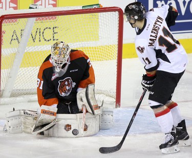 Calgary Hitmen Beck Malenstyn, right, tries to score on Medicine Hat Tigers netminder Nick Schneider, left, during their game at the Scotiabank Saddldome on February 17, 2015.