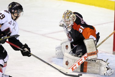 Calgary Hitmen Radel Fazleev, left, scores on Medicine Hat Tigers netminder Nick Schneider during their game at the Scotiabank Saddldome on February 17, 2015.