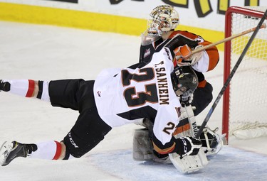 Calgary Hitmen Taylor Sanheim, left, scores on Medicine Hat Tigers netminder Nick Schneider during their game at the Scotiabank Saddldome on February 17, 2015.