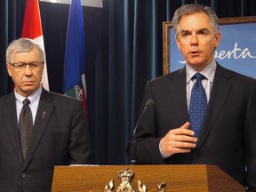 Alberta Premier Jim Prentice speaks during a news conference as Finance Minister Robin Campbell, left, looks on in Edmonton on Feb. 11, 2015.