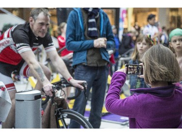 Lily Hunter, right, takes a video of her father, Simon Hunter, left, during the CANSuffer to Conquer event, in which participants ride for up to 24 consecutive hours to raise money for the fight against cancer at the Southcentre Mall in Calgary, on February 28, 2015.