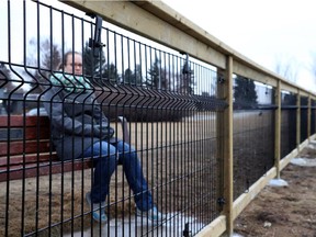 Bethany Wall looks through the fence  overlooking the Elbow River from Britannia Drive. Reader says enclosed off-leash area is too small.