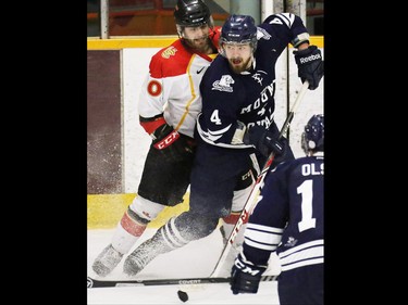 The Calgary Dinos' Ryan Harrison and the Mount Royal Cougars' Emerson Hrynyk battle in the corner during the third period of the CIS Canada West men's semifinal series at Father David Bauer Arena on Friday evening February 27, 2014.