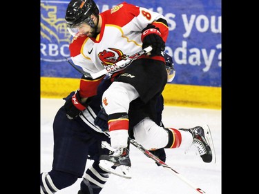 The Calgary Dinos' Grant Baker goes up and over as the Dinos played the Mount Royal Cougars during the second period the CIS Canada West men's semifinal series at Father David Bauer Arena on Friday evening February 27, 2014.