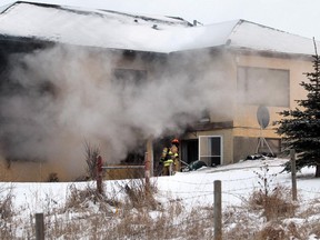 A firefighter prepares to go into a burning house as Fire departments from the Foothills, Okotoks and High River were all on scene helping to fight a house fire in a property overlooking the Okotoks overpass on the east side of Highway 2 Sunday, February 1, 2015. The property has large for sale signs on it.