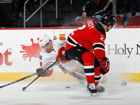 Josh Jooris of the Calgary Flames hits the ice while being checked by Marek Zidlicky of the New Jersey Devils during Wednesday's game. Jooris is one of 22 players to make their NHL debuts with the Flames under Bob Hartley's tenure.