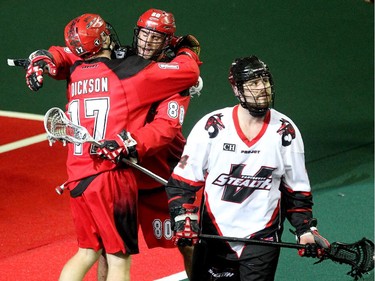 Calgary Roughnecks players forward Curtis Dickson and transition Peter McFetridge celebrated one of the Roughnecks goals as Vancouver Stealth defenceman Rory Smith walked away during first half National Lacrosse League action at the Scotiabank Saddledome on February 21, 2015.