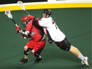 Calgary Roughnecks forward Dane Dobbie and Vancouver Stealth forward Tyler Digby battled as Dobbie set up his goal during second half National Lacrosse League action at the Scotiabank Saddledome on February 21, 2015. The Roughnecks broke their winless season with a 16-13 win over Vancouver.