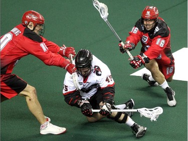 Calgary Roughnecks players transition Curtis Manning, left, and defenceman Mike Carnegie put pressure on Vancouver Stealth forward Corey Small during first half National Lacrosse League action at the Scotiabank Saddledome on February 21, 2015.