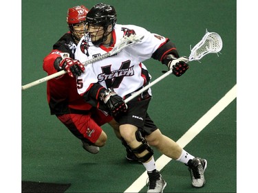 Calgary Roughnecks defenceman Mike Carnegie, left, put some pressure on Vancouver Stealth forward Corey Small during first half National Lacrosse League action at the Scotiabank Saddledome on February 21, 2015.