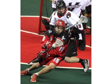 Calgary Roughnecks forward Shawn Evans tried to avoid the check of Vancouver Stealth defenceman Justin Salt during first half National Lacrosse League action at the Scotiabank Saddledome on February 21, 2015.