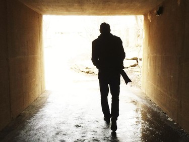 A man with a camera is silhouetted as he walks through an underground tunnel on a warm February day at the Calgary Zoo.