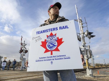 Eric Wood, a train conductor and CP Rail employee of 21 years, wears sign as he and dozens of others walk the edge of the Ogden rail yard as they strike in Calgary, on February 15, 2015.