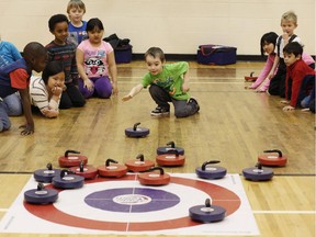 Kayel Atton, 6, a Grade 1 student at St. Damien School in Calgary, tries curling during the Rocks and Rings program at his school.