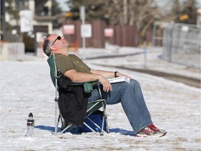 Calgarian Erik van Kuppeveld takes a break from reading and takes in the sunshine and 9C temperatures during Chinook weather conditions in Calgary on Feb. 12, 2015.