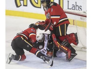 Anaheim Ducks' Kyle Palmieri  and Calgary Flames' Markus Granlund slide into Flames goalie Jonas Hiller after chasing down the puck during game action at the Saddledome in Calgary, on February 20, 2015. --  (Crystal Schick/Calgary Herald) (For Sports story by  TBA) 00057784A