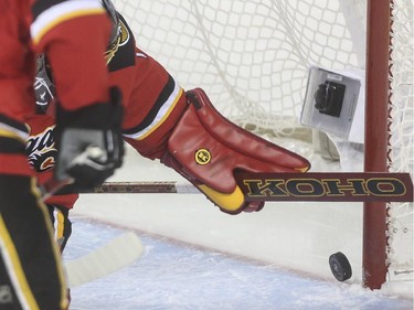 Calgary Flames goalie Jonas Hiller reaches for the puck after it bounced off the back of his leg and across the goal line during game action against the Anaheim Ducks at the Saddledome in Calgary, on February 20, 2015.