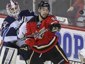 Winnipeg Jets goalie Michael Hutchinson, left, and Calgary Flames forward Josh Jooris watch a loose flying puck during Monday's game. The Flames chased Hutchinson from the net midway through the third period when they gained a 4-1 lead.