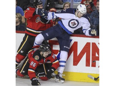 Things get messy as Winnipeg Jets' Adam Lowry, right, get caught up in the boards with Calgary Flames' Josh Jooris, bottom, and Deryk Engellan during game action at the Saddledome in Calgary, on February 2, 2015.