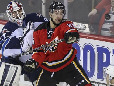 Winnipeg Jets' goalie Michael Hutchinson, left, and Calgary Flames' Josh Jooris watch a loose flying puck during game action at the Saddledome in Calgary, on February 2, 2015.