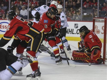 Calgary Flames Dennis Wideman, 6, tries to knock away the loose puck as Calgary Flames goalie Jonas Hiller tries to make the save with pressure from the San Jose Sharks from all around during second period action at the Saddledome in Calgary, on February 4, 2015.