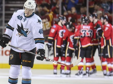 San Jose Sharks' Tomas Hertl, left, skates to his bench as the Flames celebrate scoring their third goal in the second period at the Saddledome in Calgary, on February 4, 2015.