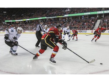 Calgary Flames Kris Russell, centre, carries the puck after scoring his first goal of the season during game action against the San Jose Sharks at the Saddledome in Calgary, on February 4, 2015.