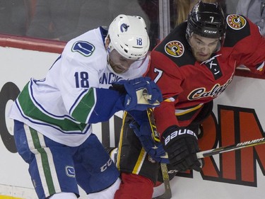 Calgary Flames' TJ Brodie battle Vancouver Canucks Ryan Stanton in the boards during game action at the Saddledome in Calgary, on February 14, 2015.