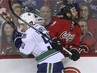 Calgary Flames' Deryk Engelland taks a hit from Vancouver Canucks' Bo Horvat during game action at the Saddledome in Calgary, on February 14, 2015.