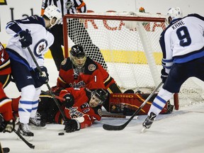 Winnipeg Jets Adam Lowry, left, and Jacob Trouba, right, try to score on Calgary Flames goalie Jonas Hiller, second from left, but Flames D-man Kris Russell is also in the way. Russell blocked nine shots against the Jets to add to his NHL-leading total.