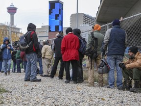 Homeless people line up outside the Drop In shelter to catch a bus to another shelter in Calgary, on October 26, 2014.