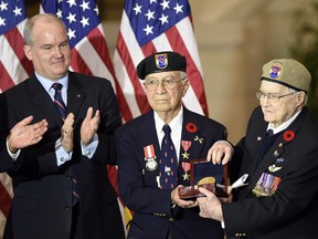 Canadian Minister of Veterans Affairs Erin O'Toole, left, and Senate Majority Leader Mitch McConnell of Ky, right, applaud Eugene Gutierrez, Jr., second from left, and Charles Mann, second from right, after presenting them with the Congressional Gold Medal for members of the First Special Service Force during a ceremony on Capitol Hill in Washington, Tuesday, Feb. 3, 2015. The fearlessness and bravery of the famed "Devil's Brigade" unit contributed to the liberation of Europe and an end to World War II.