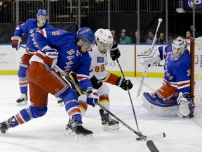 New York Rangers' Marc Staal fights for control of the puck with Calgary Flames' Josh Jooris as goalie Cam Talbot watches during their Tuesday night meeting. Talbot recorded a shutout in New York's 1-0 win.