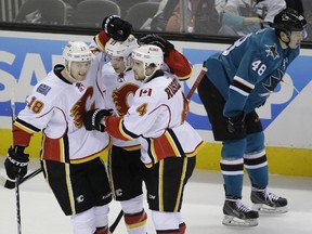 Calgary Flames' Mason Raymond (21) celebrates his goal with teammates Matt Stajan (18) and Kris Russell (4) as San Jose Sharks' Tomas Hertl (48) skates by during the first period on Monday.