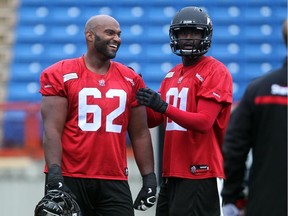 Calgary Stampeders offensive lineman Edwin Harrison, left, jokes with teammate Jabari Arthur during a practice last August. Harrison re-signed with the Stamps on Wednesday.