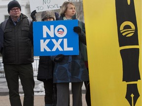 Melinda Pierce, center, with the Sierra Club, holds a "No KXL" sign, next to a large poster of a pen as she gathers with other opponents of Keystone XL oil pipeline to celebrate President Barack Obama's veto of the legislation outside the White House in Washington on Feb. 24, 2015.