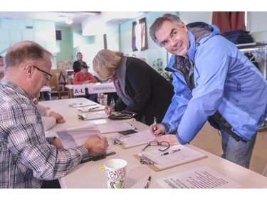 Premier Jim Prentice registers to cast his ballot along with his wife Karen Prentice, centre, in his home constituency of Calgary-Mountain View at the Renfrew United Church in Calgary, on February 21, 2015.