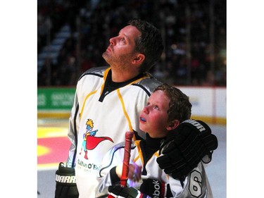 An emotional Rod O'Brien and his son Luke watch a video on the jumbotron of Luke's brother Nathan before the start of the  Nathan O'Brien Children's Foundation hockey game Thursday February 5, 2015 at the Saddledome. A team made up of Nathan's family, local police and politicians took on a Calgary Flames Alumni squad.