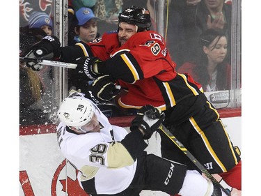 Derek Engelland of the Calgary Flames nails centre Zach Still of the Pittsburgh Penguins behind the Flames net during the third period at the Saddledome Friday February 6, 2015.