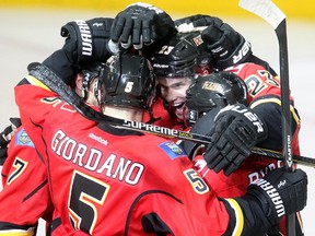 Calgary Flames players, including Sean Monahan, centre, and Mark Giordano, celebrate TJ Brodie's overtime goal, which gave them a 4-3 win over the Boston Bruins at the Saddledome on Monday.