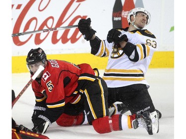 Calgary Flames captain Mark Giordano slams winger Brad Marchand of the Boston Bruins in the Flames end during the second period at the Saddledome Monday February 16, 2015.