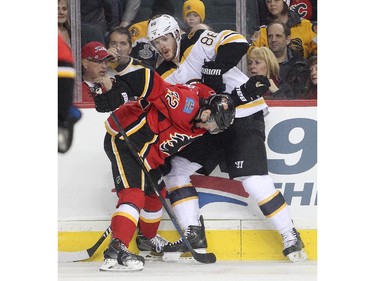 Paul Byron of the Calgary Flames and defenceman Kevan Miller of the Boston Bruins do battle against the obards in the Flames end during the first period at the Saddledome Monday February 16, 2015.